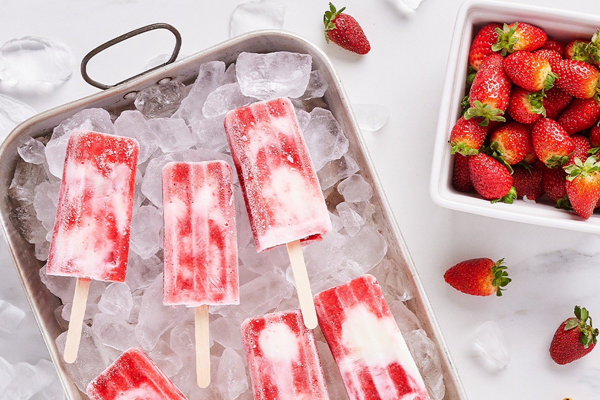 Strawberries and cream ice pops recipe sitting over ice