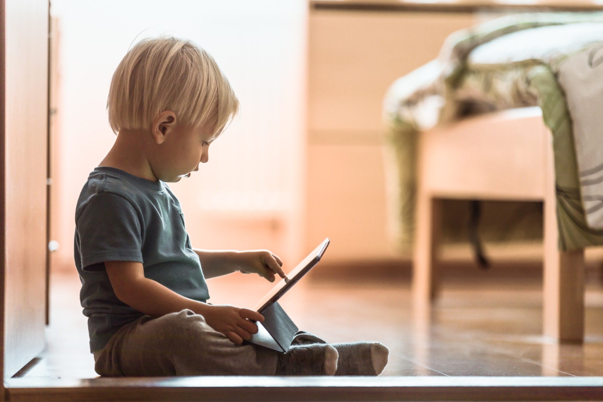 Preschooler looks at a tablet on the floor, begging the question how much screen time should your preschooler be allowed each day?