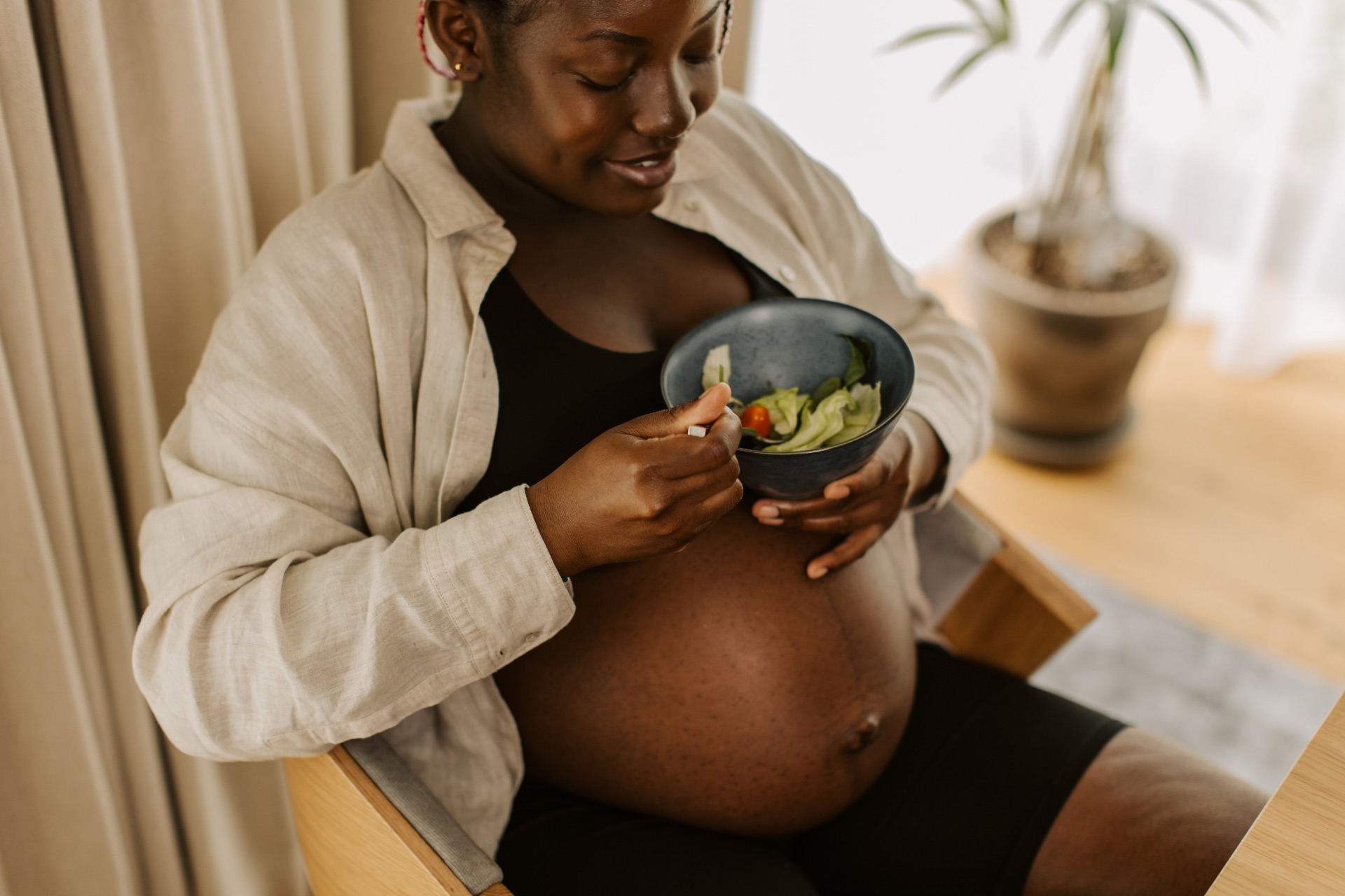 a pregnant woman holding a bowl of food